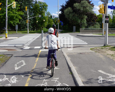 Radfahrer (Mutter und Sohn) auf dem Trillium Radweg, mit einem grünen Licht southbound in Carling Avenue, Ottawa, Ontario, Kanada, zu überqueren. Stockfoto