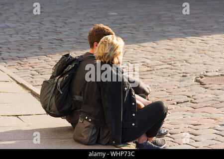 Ein Paar sitzt auf dem Bürgersteig des Rathausplatz in der Abendsonne in der Altstadt von Tallinn Stockfoto