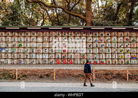 DEC 5, 2019 Tokyo, Japan - Sake Fässer Wand oder Kazaridaru der Meiji Jingu-Schrein unter grossen Baum mit Touristen zu Fuß weiter. Verwendung als Geschenk zu Shinto Gott Stockfoto