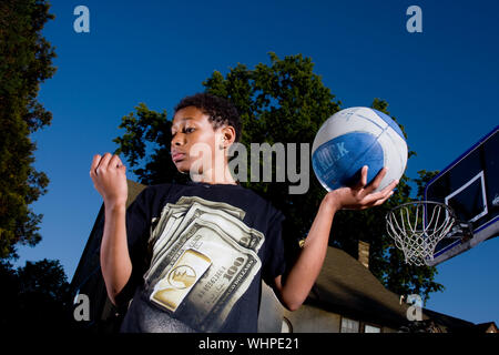 Elf Jahre alte African American Boy spielt Basketball an seinem Vorstadthaus außerhalb Philadelphia PA Stockfoto