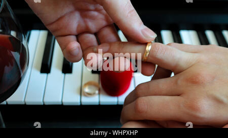 Liebhaber Heiraten, exchange Verlobungsring auf dem Hintergrund einer Piano, ein Glas Rotwein und ein rotes Kästchen in der Form eines Herzens. Der Tag des Wir Stockfoto
