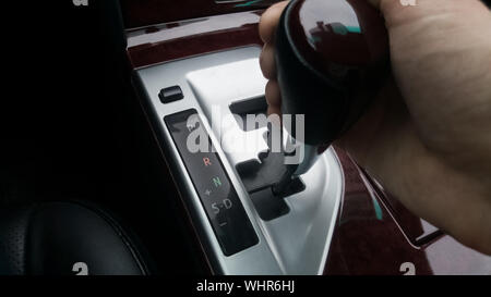 Die Hand auf der Wahlschalter des Automatikgetriebes. Positionieren Sie das Laufwerk auf dem Automatikgetriebe. Stockfoto