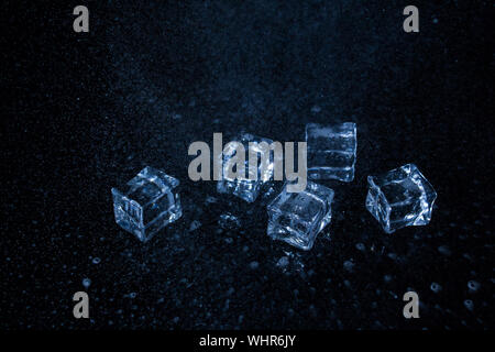 Eiswürfel auf einem schwarzen Hintergrund mit Spritzern und Tropfen. Stockfoto
