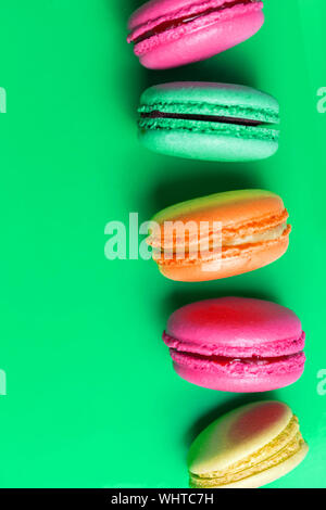 Nahaufnahme der bunte Makronen auf grünem Hintergrund, Ansicht von oben. Süßes Gebäck, Kekse Stockfoto