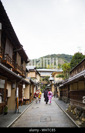 Einige Menschen in der traditionellen Kimono gekleidet sind zu Fuß durch die Straßen von Kyoto. Stockfoto