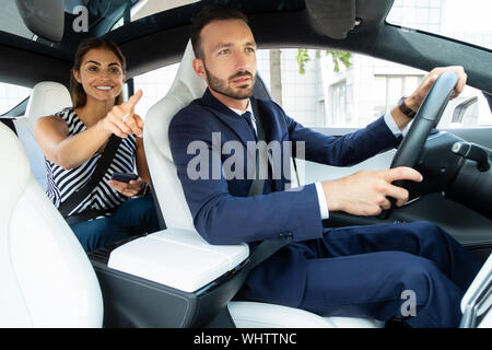 Lächelnde Frau mit der Route während Mann fahren Stockfoto