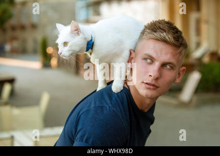 Wollen über alles zu wissen. Katze steht auf der Rückseite seines Besitzers. Glückliche Menschen auf Spaziergang mit katze Haustier. Muskulöse Mann niedlich Rassekatze. Happy Cat owne Stockfoto