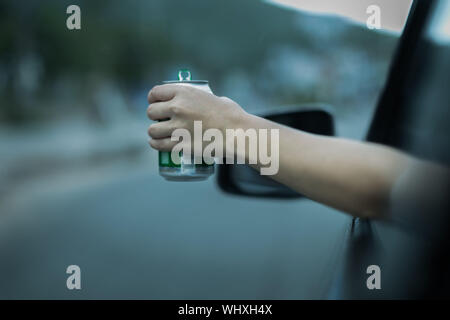 Holding ein Bier draußen ein Auto Fenster. die Beschleunigung. blue Tone. Stockfoto