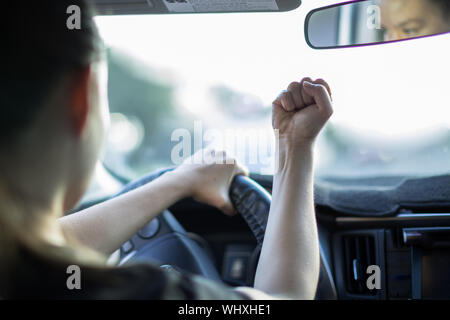 Ein wütender Erwachsener im Auto sitzen, halten eine Faust auf einen anderen Treiber. Stockfoto