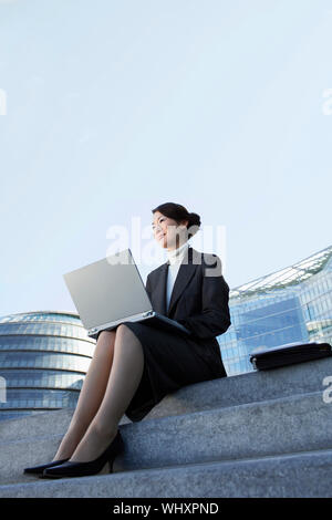 Low Angle View einer jungen Unternehmerin mit Laptop im Freien Schritte Stockfoto