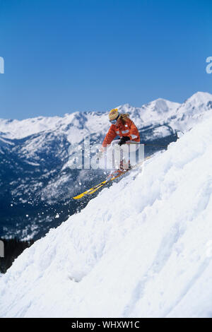 Seitenansicht eines Skifahrers unten Ski Slope gegen Berg und strahlend blauer Himmel Stockfoto