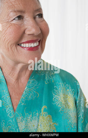 Nahaufnahme von einem fröhlichen älteren Frau, die sich gegen die weißen Hintergrund suchen Stockfoto