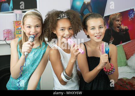 Multiethnischen junge Mädchen mit Bürsten als Mikrofone an einem Slumber Party zu singen Stockfoto