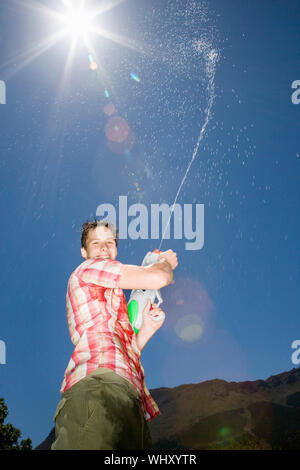 Portrait von Teenager Sprühwasser aus Gewehr in die Luft Stockfoto