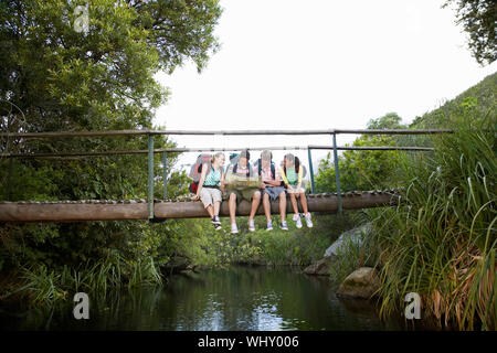 Teenager Jungs und Mädchen mit Rucksäcken lesen Karte auf der Brücke im Wald Stockfoto