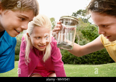 Jungen und Mädchen an der Schlange in Jar im Freien suchen Stockfoto