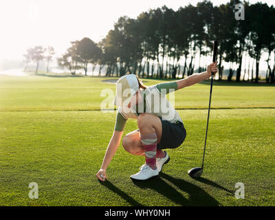 Volle Länge des jungen weiblichen Golfspieler die Kugel am T-Stück Stockfoto