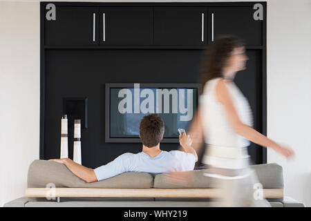 Bewegung der Frau vorbei über die Fernbedienung während TV zu Hause aufpassen man Unscharf Stockfoto