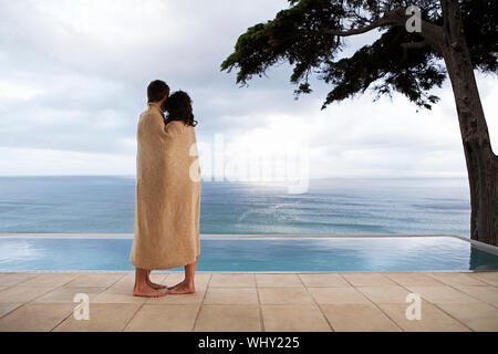 Seitenansicht des jungen Paares in der Decke eingewickelt an infinity Pool suchen Stockfoto