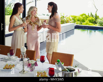 Drei junge weibliche Freunde mit Champagner Flöten beim Abendessen Partei Stockfoto