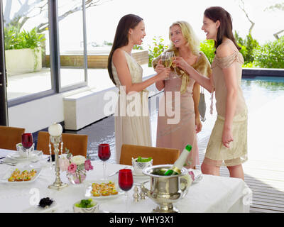 Drei junge weibliche Freunde toasten Champagnergläser zum Abendessen Partei Stockfoto