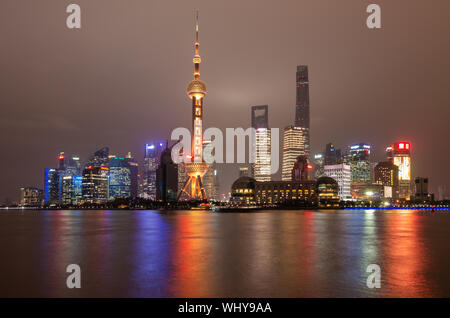 Skyline der Stadt Shanghai Pudong bei Nacht mit dem Oriental Pearl TV Tower und Lichtreflexionen des Huangpu Flusses, Shanghai, China Stockfoto