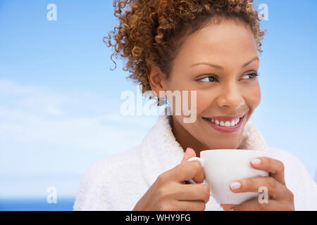 Schöne junge Frau im Bademantel in Kaffee im Freien Stockfoto