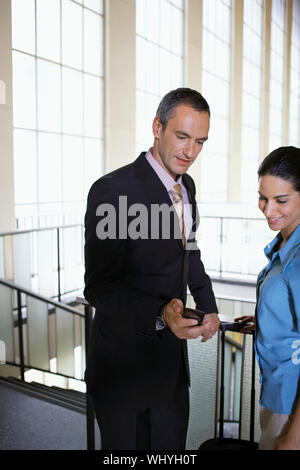 Geschäftsmann, Frau Handy im Flughafen Lobby Stockfoto