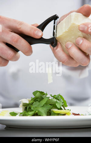 Closeup Mittelteil eines männlichen Chef Gitter Käse Salat Stockfoto