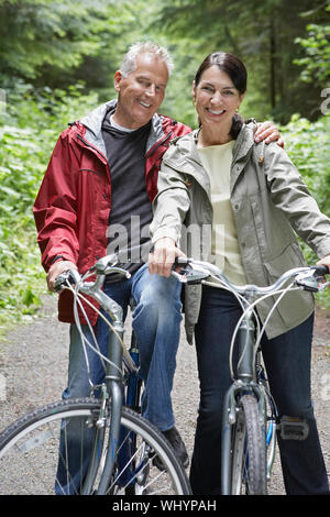 Portrait von Happy reifer Mann und Frau mittleren Alters mit den Fahrrädern, die in der Gesamtstruktur Stockfoto