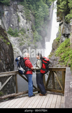 Volle Länge Seite Blick auf einen Mann und eine Frau in der Nähe von Wasserfall an jedem anderen Suchen Stockfoto
