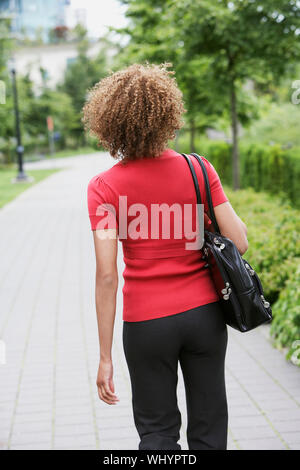 Rückansicht eines geschweiften behaarte Frau zu Fuß durch die Stadt park Stockfoto