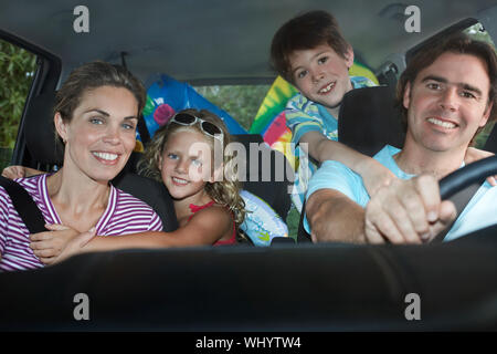 Portrait von lächelnden Ehepaar mit zwei Kindern im Auto. Stockfoto