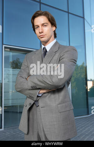 Portrait von selbstbewussten jungen Geschäftsmann stand mit verschränkten Armen außerhalb der Stockfoto