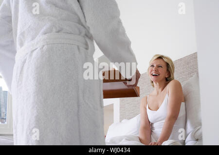 Mittelteil des Menschen, das Frühstück zu fröhliche Frau im Bett Stockfoto