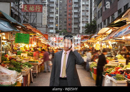 Portrait von hübscher junger Geschäftsmann mit Mobiltelefon am Markt Stockfoto