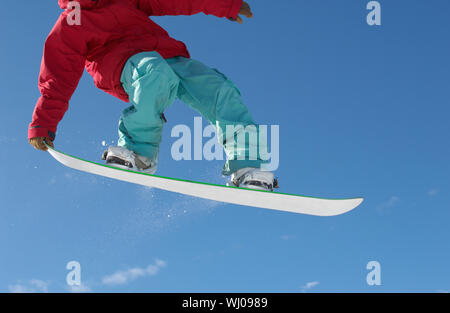 Niedrige Abschnitt der männlichen Snowboarder gegen den blauen Himmel springen Stockfoto