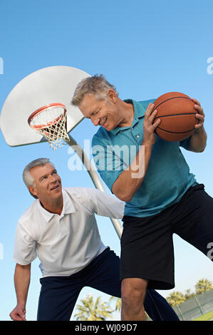 Alte Männer spielen Basketball auf Freiplatz Stockfoto