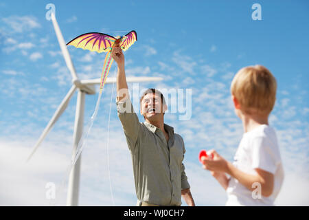 Vater und Sohn (7-9) spielen mit Kite im Windpark Stockfoto