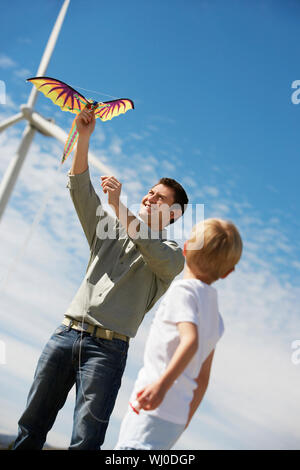 Vater und Sohn (7-9) spielen mit Kite im Windpark Stockfoto