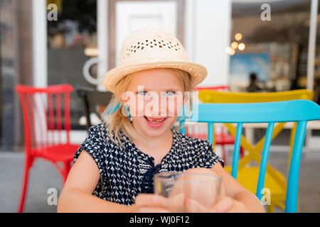 Porträt eines Kindes, das eine gute Zeit auf ein Café Terrasse. Mädchen ist einen Hut tragen, für die Sonne, Spaß mit der Familie auf einem Cafe Terrasse. Stockfoto