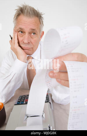 Ältere männliche Buchhalter mit seiner Berechnungen gelangweilt Stockfoto