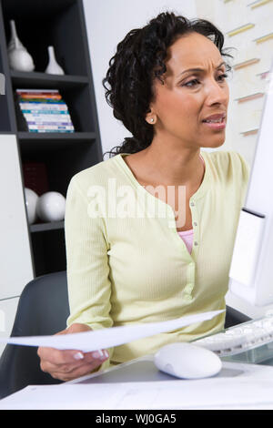 Angespannt reife Frau mit dem Dokument am Bildschirm auf der Suche Stockfoto