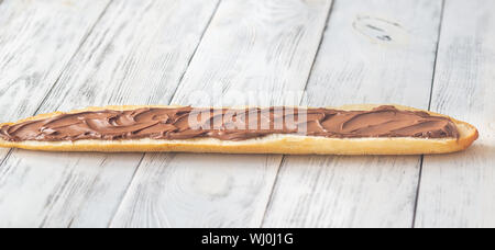 Die Hälfte der Baguette mit Schokoladencreme auf dem hölzernen Tisch Stockfoto