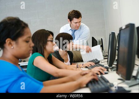 Männliche Professor mit Studentinnen in Computer Lab Stockfoto