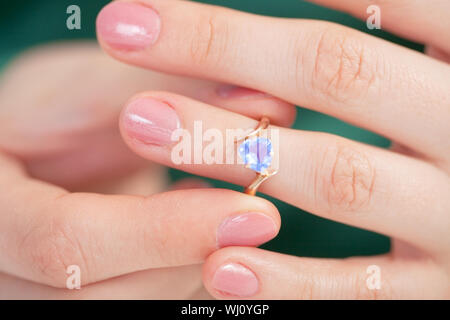 Der Goldene Ring mit einem dunkelblauen Juwel versuchen auf einem Finger Stockfoto