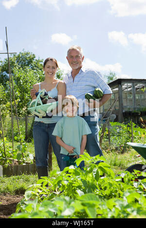 Portrait von glücklichen jungen mit Mutter und Großvater holding Gemüse in Gemeinschaft garten