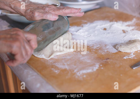 Die Hand der alten Frau auf abgeflacht Teig. Stockfoto