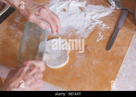 Hände einer alten Frau auf der abgeflachten Teig. Stockfoto