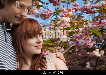 Romantische junge Paar stehen unter Cherry Blossom tree Stockfoto